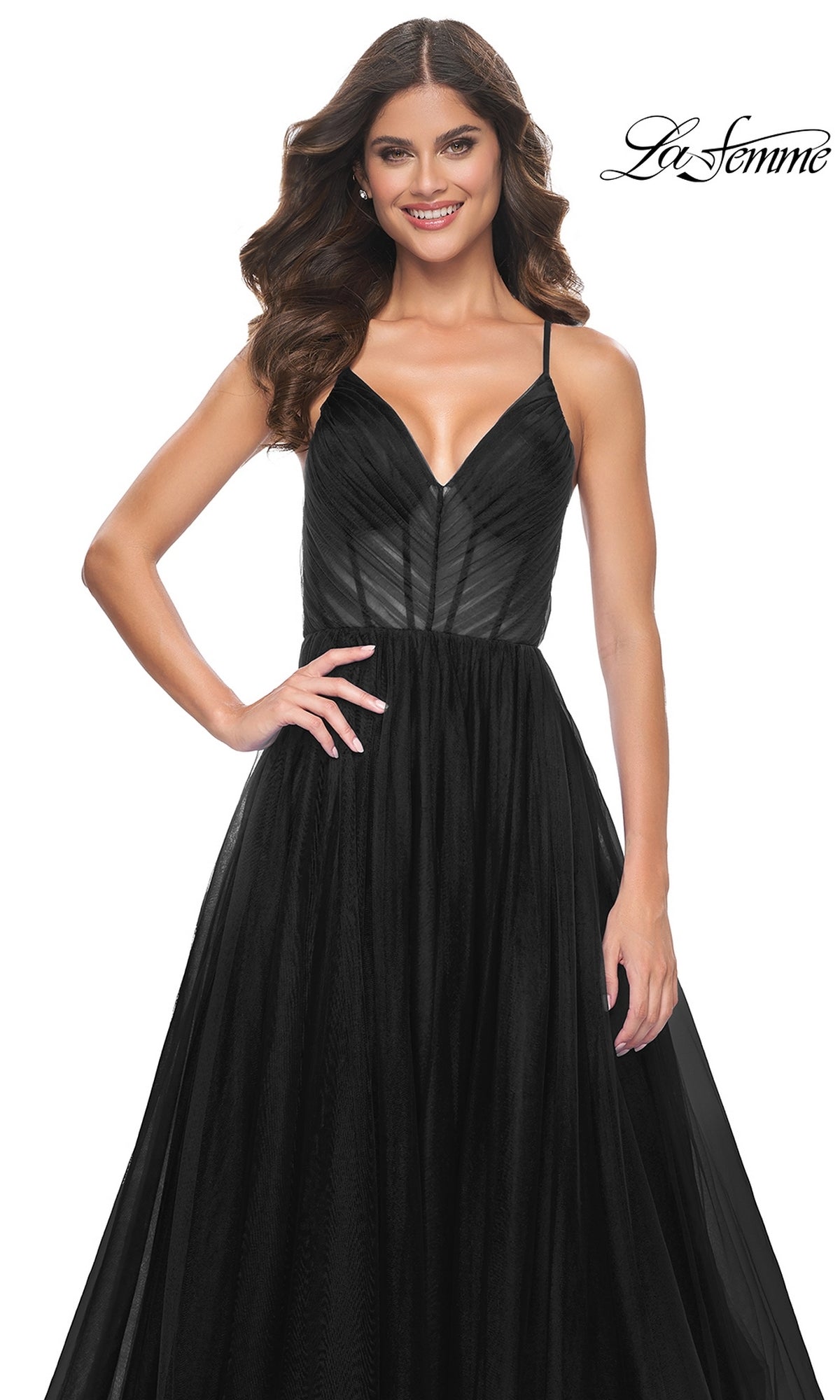 A woman smiles against a white background in the La Femme Sheer-Waist Long Prom Ball Gown 31457, a sleeveless black designer dress with thin straps and sheer overlay. The